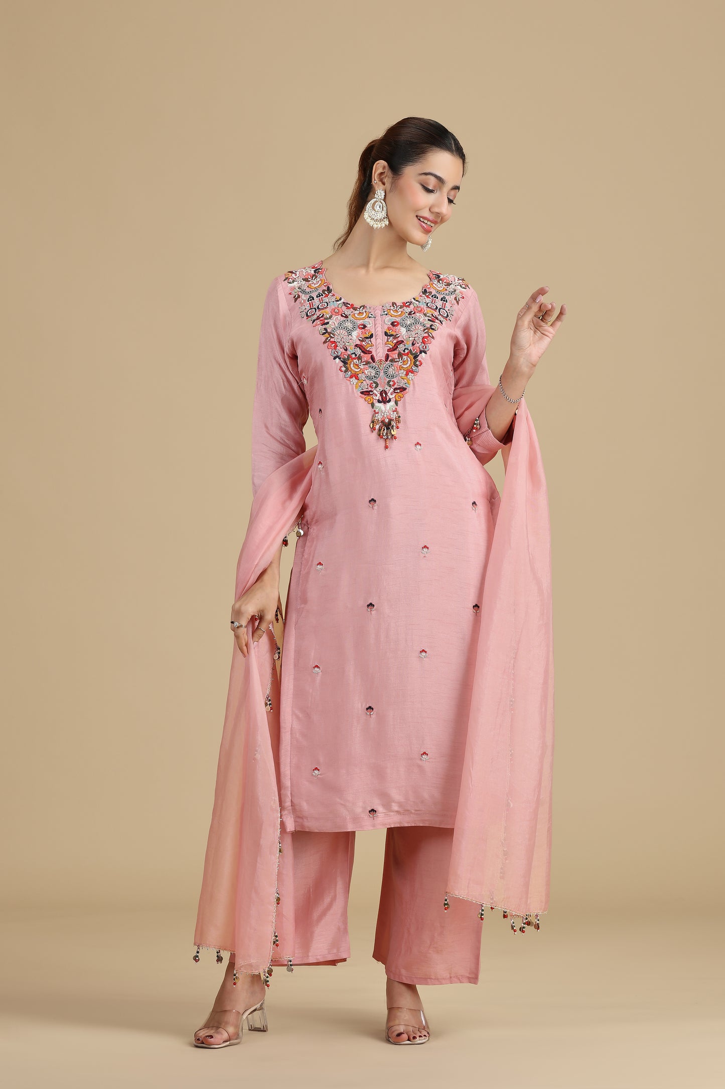 Woman wearing a pink embroidered traditional outfit on a beige background