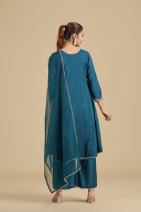 Woman wearing a teal traditional outfit with a beige background