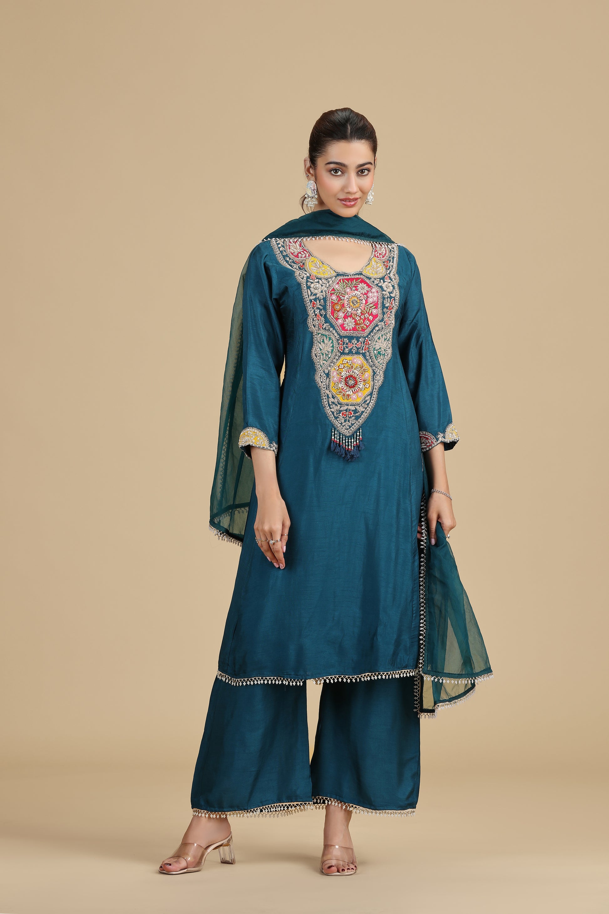 Woman wearing a peacock blue embroidered kurta on a beige background