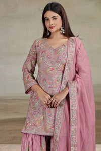Woman wearing a ready pink crepe salwar suit with printed and zari detailing