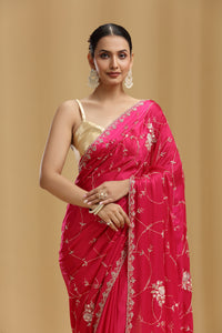 Woman wearing a pink crepe saree with floral patterns on a beige background