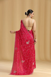Woman wearing a pink saree with a gold blouse against a beige background