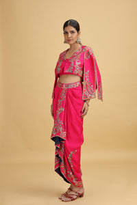 Woman wearing a bright pink dola suit with intricate designs on a beige background