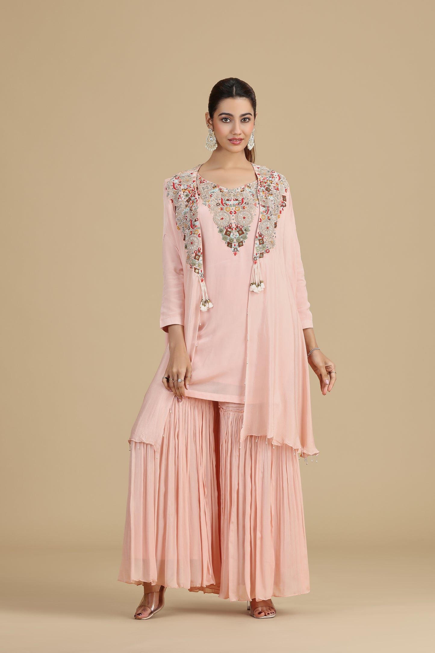 Woman wearing a pink traditional outfit with floral embroidery on a beige background