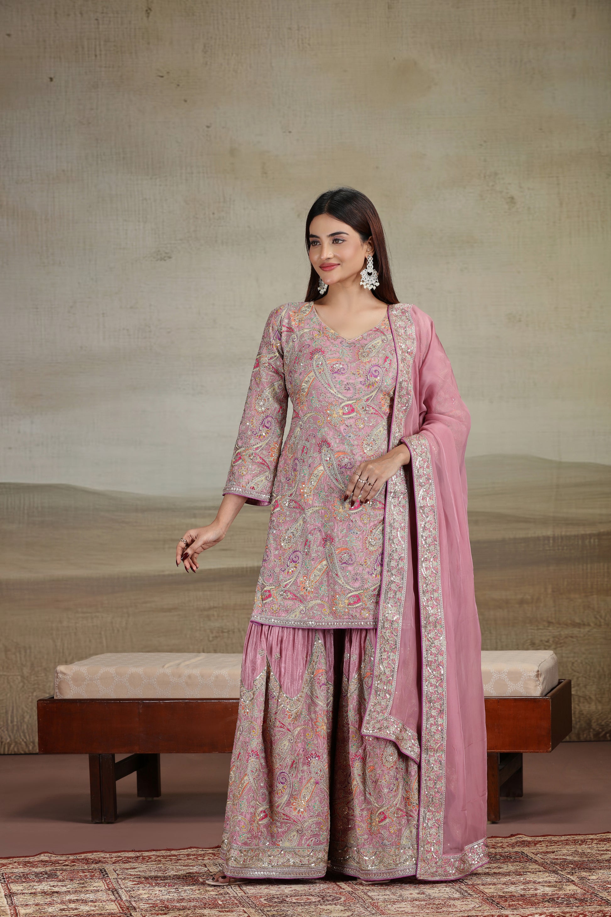 Woman in a pink traditional outfit standing against a neutral background