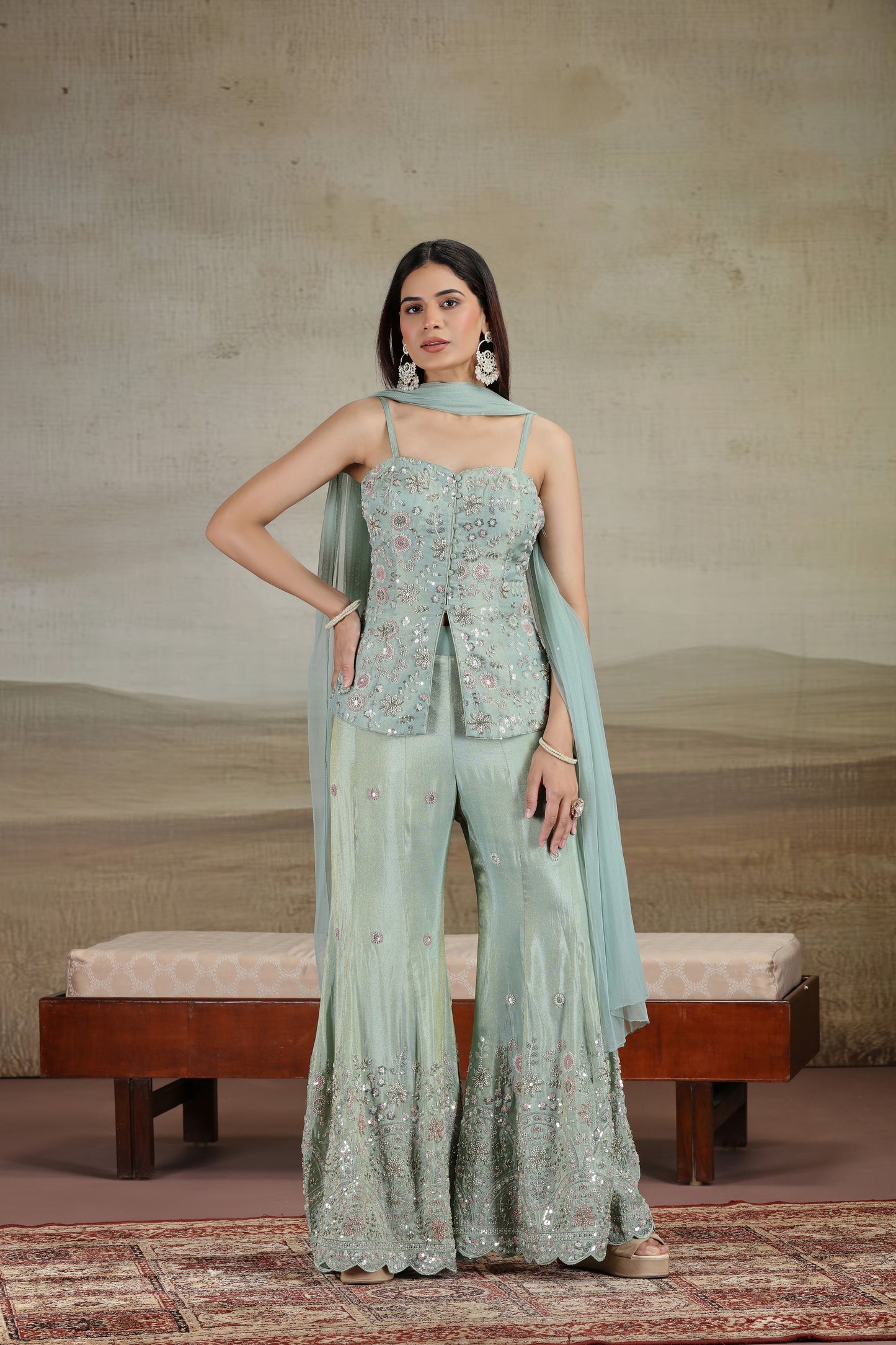 Woman in a light green traditional outfit with a matching dupatta against a neutral background