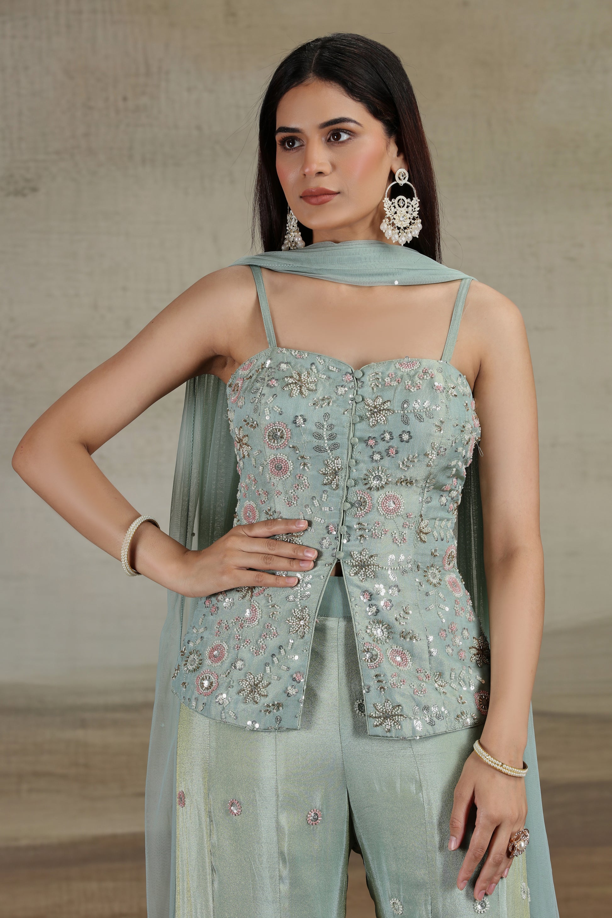 Woman wearing a pista green embroidered top and matching dupatta against a neutral background