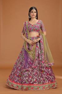 Woman wearing a traditional floral lehenga with a purple blouse on a brown background