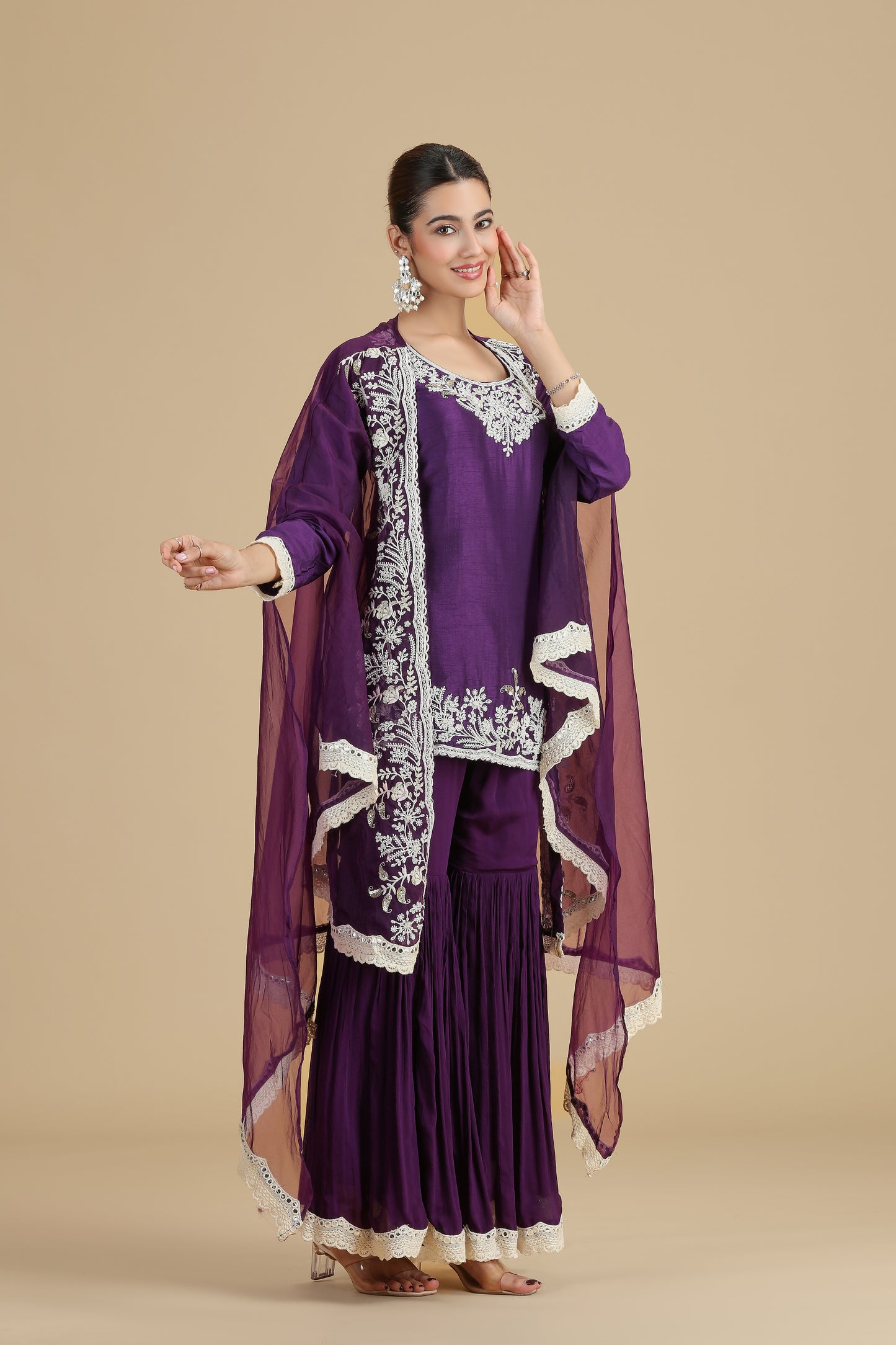 Woman wearing a purple printed kurta with dupatta with white embroidery on a beige background
