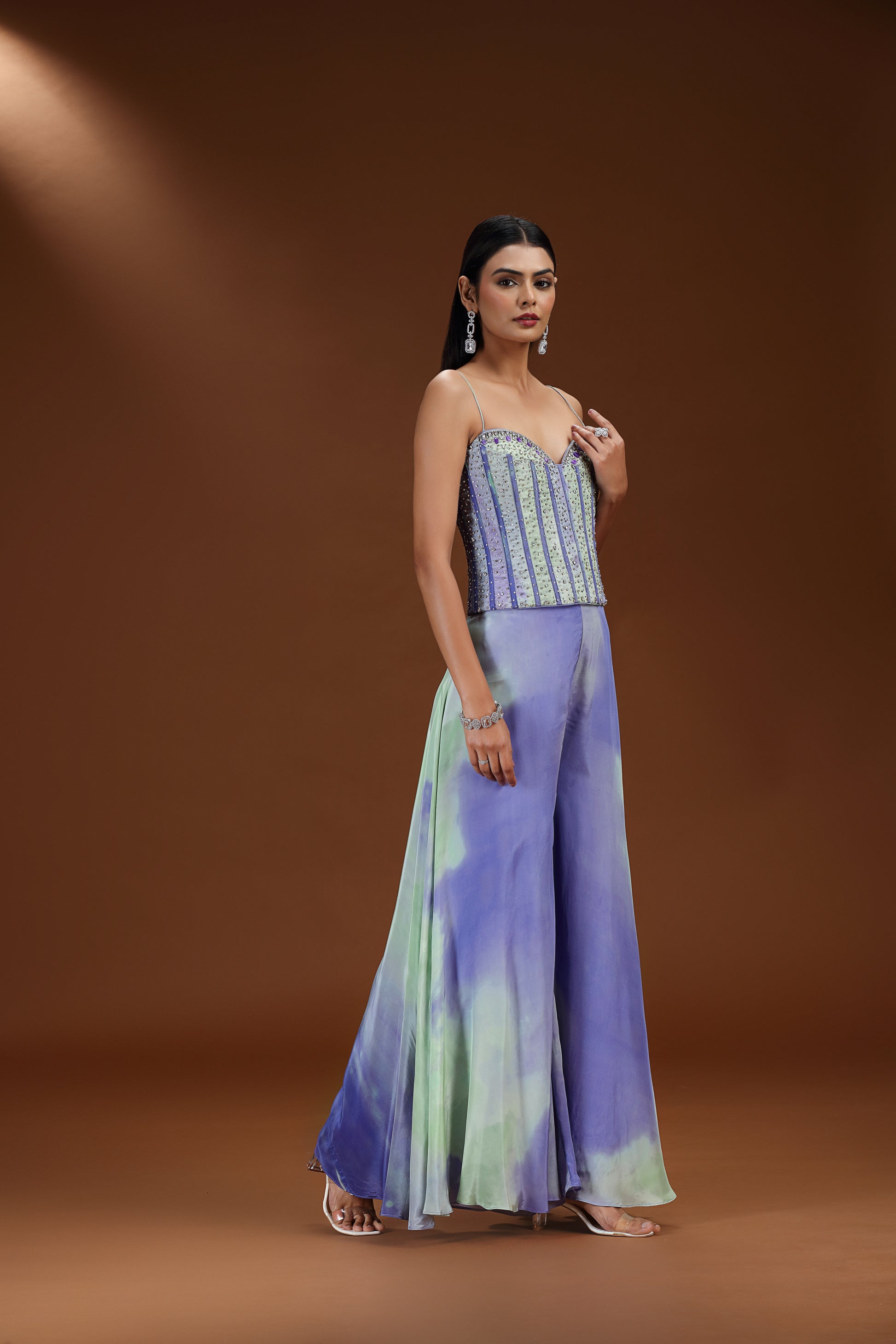 Woman wearing a strapless top and wide-leg pants with a tie-dye pattern on a brown background