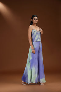 Woman wearing a strapless top and wide-leg pants with a tie-dye pattern on a brown background