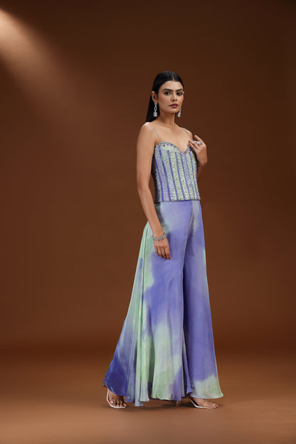 Woman wearing a strapless top and wide-leg pants with a tie-dye pattern on a brown background