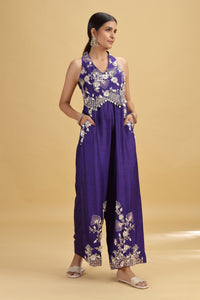 Woman wearing a purple floral jumpsuit on a beige background