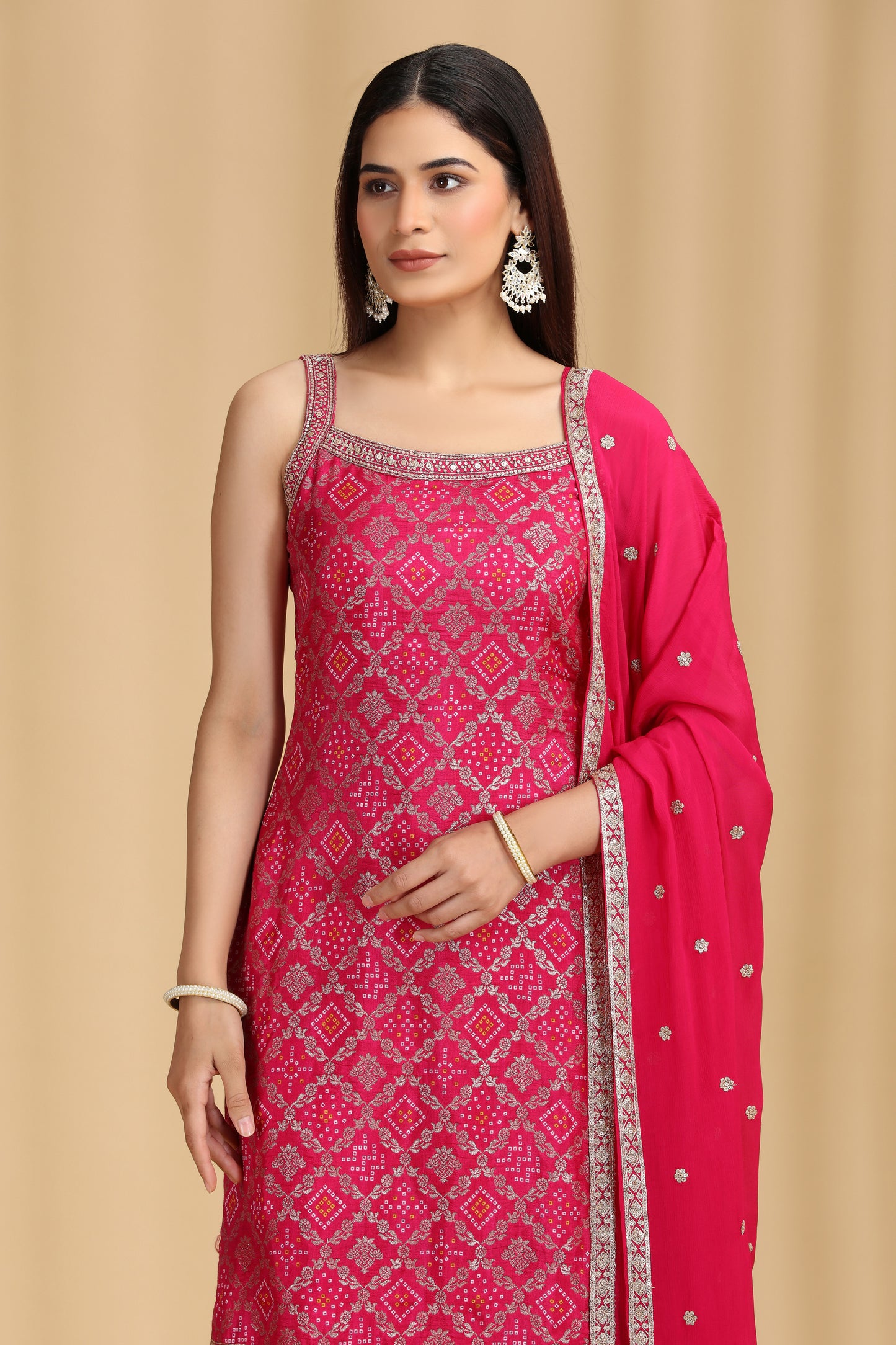 Woman wearing a pink traditional outfit with intricate patterns on a beige background
