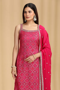 Woman wearing a pink traditional outfit with intricate patterns on a beige background