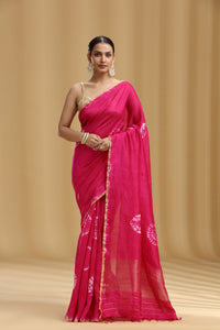 Woman wearing a bright rani pink saree with a beige background