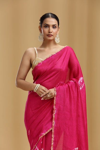 Woman wearing a rani pink silk saree with a beige background