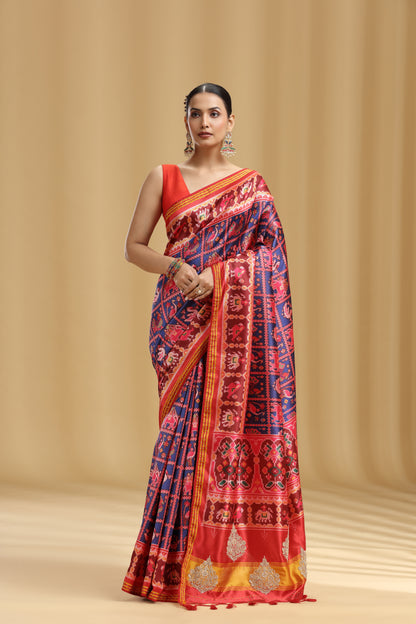 Woman wearing a traditional saree with a red and blue pattern on a beige background