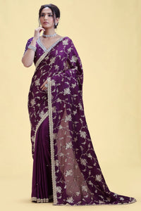 Woman wearing a purple saree with floral patterns on a beige background