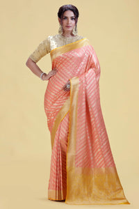 Woman wearing a pink and yellow saree on a beige background