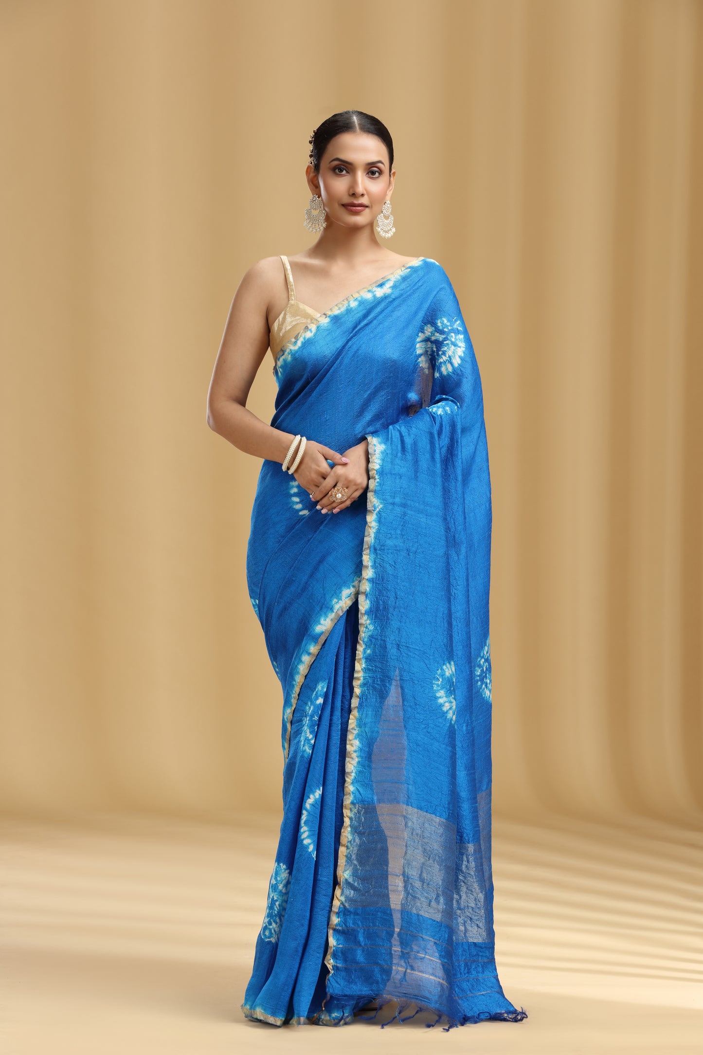 Woman wearing a blue saree with a beige background
