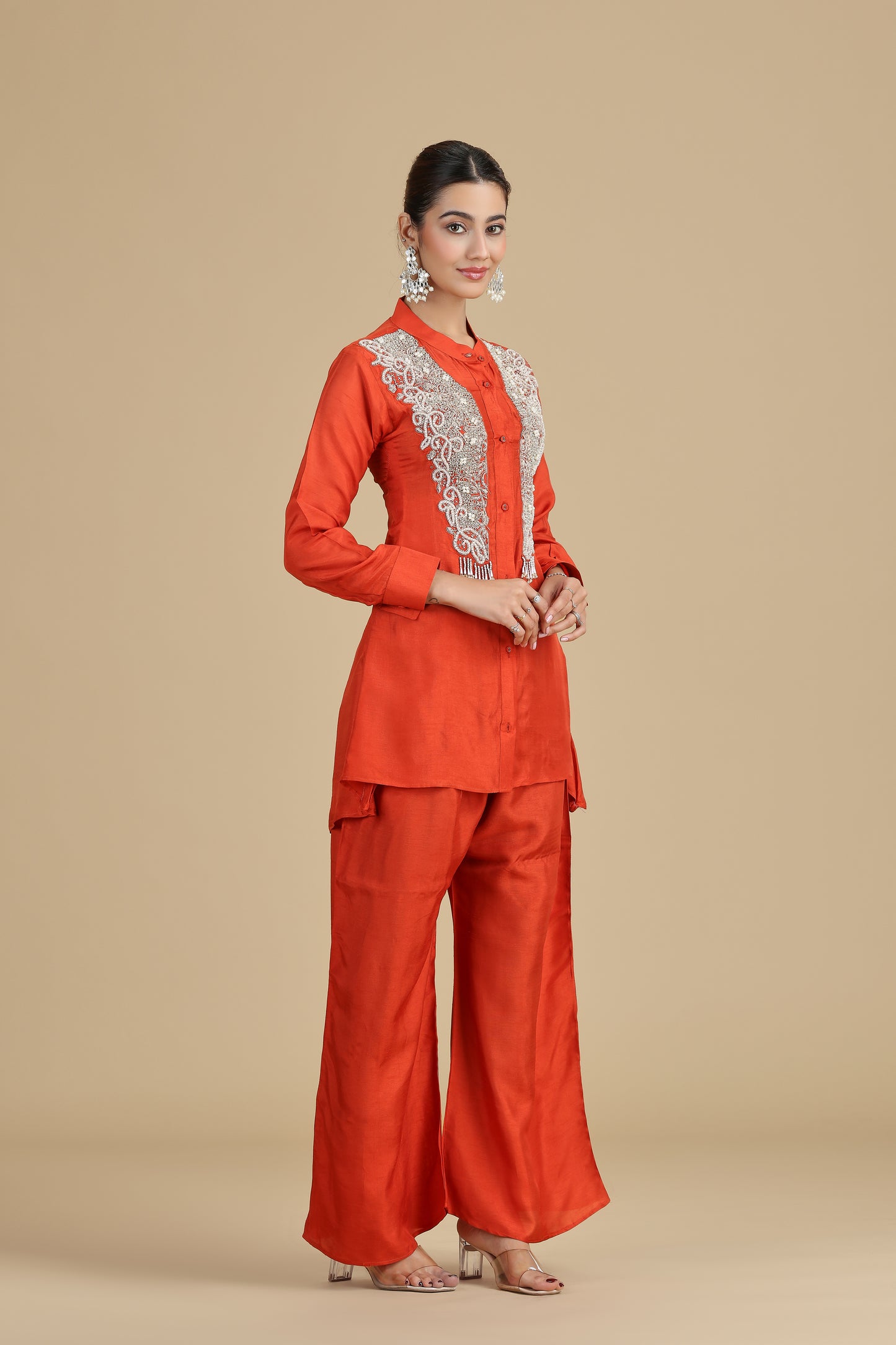 Woman wearing an orange outfit with lace details on a beige background