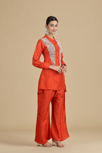 Woman wearing an orange outfit with lace details on a beige background