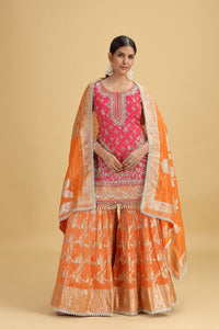 Woman wearing a traditional orange and pink salwar suit