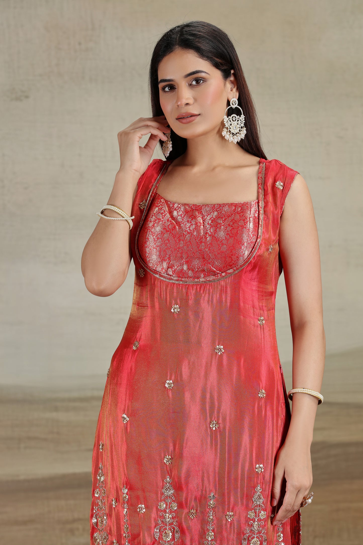 Woman wearing a red embroidered dress with a neutral background