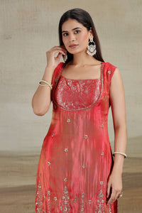 Woman wearing a red embroidered dress with a neutral background
