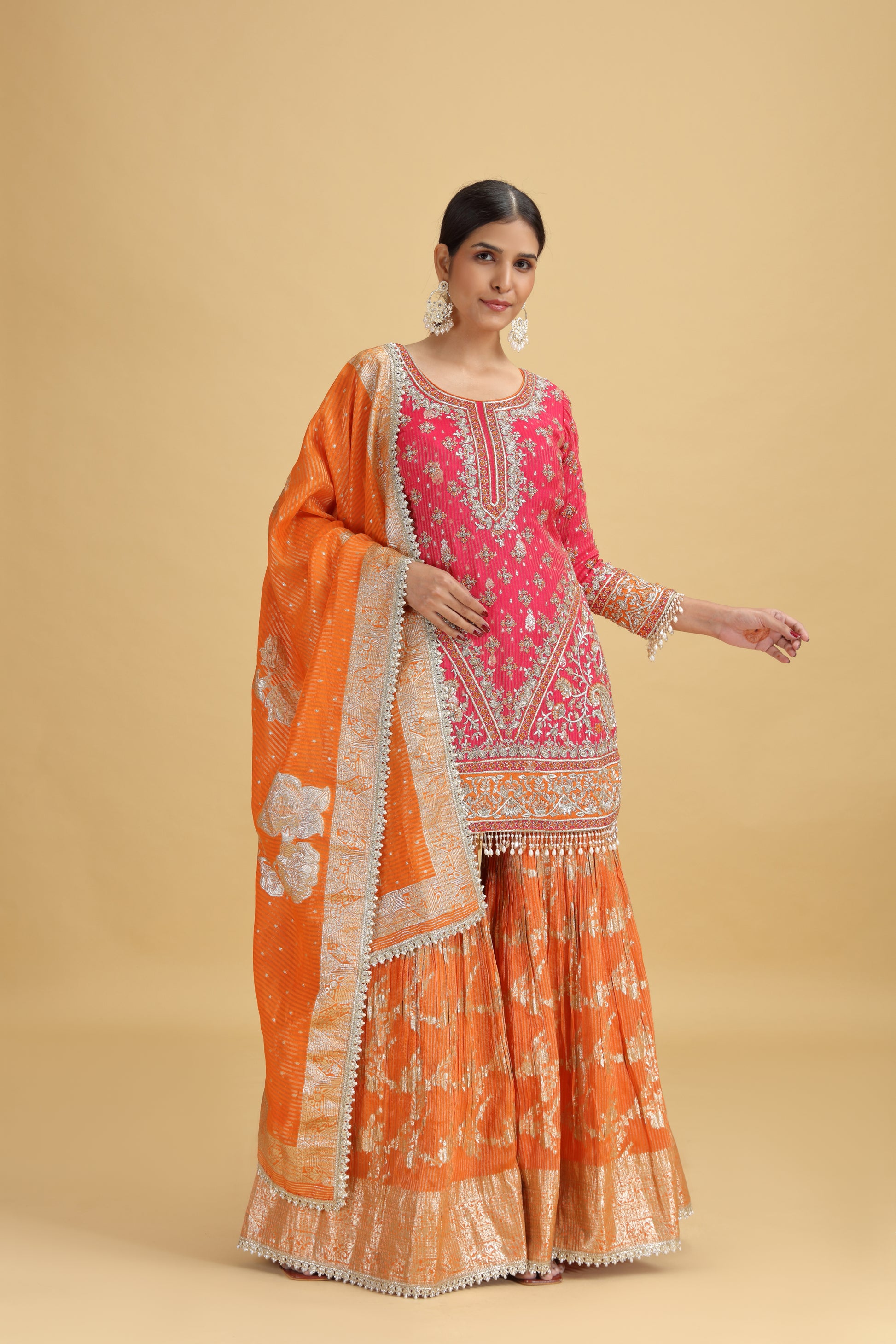 Woman wearing an orange and pink traditional outfit on a beige background