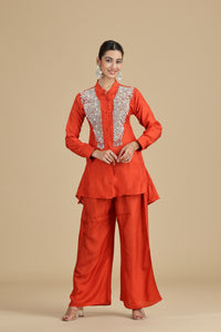 Woman wearing a orange kurta traditional outfit with intricate white embroidery on a beige background