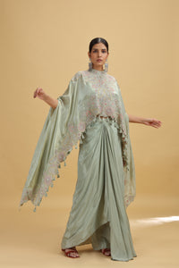 Woman wearing a light green salwar suit with a matching blouse on a beige background