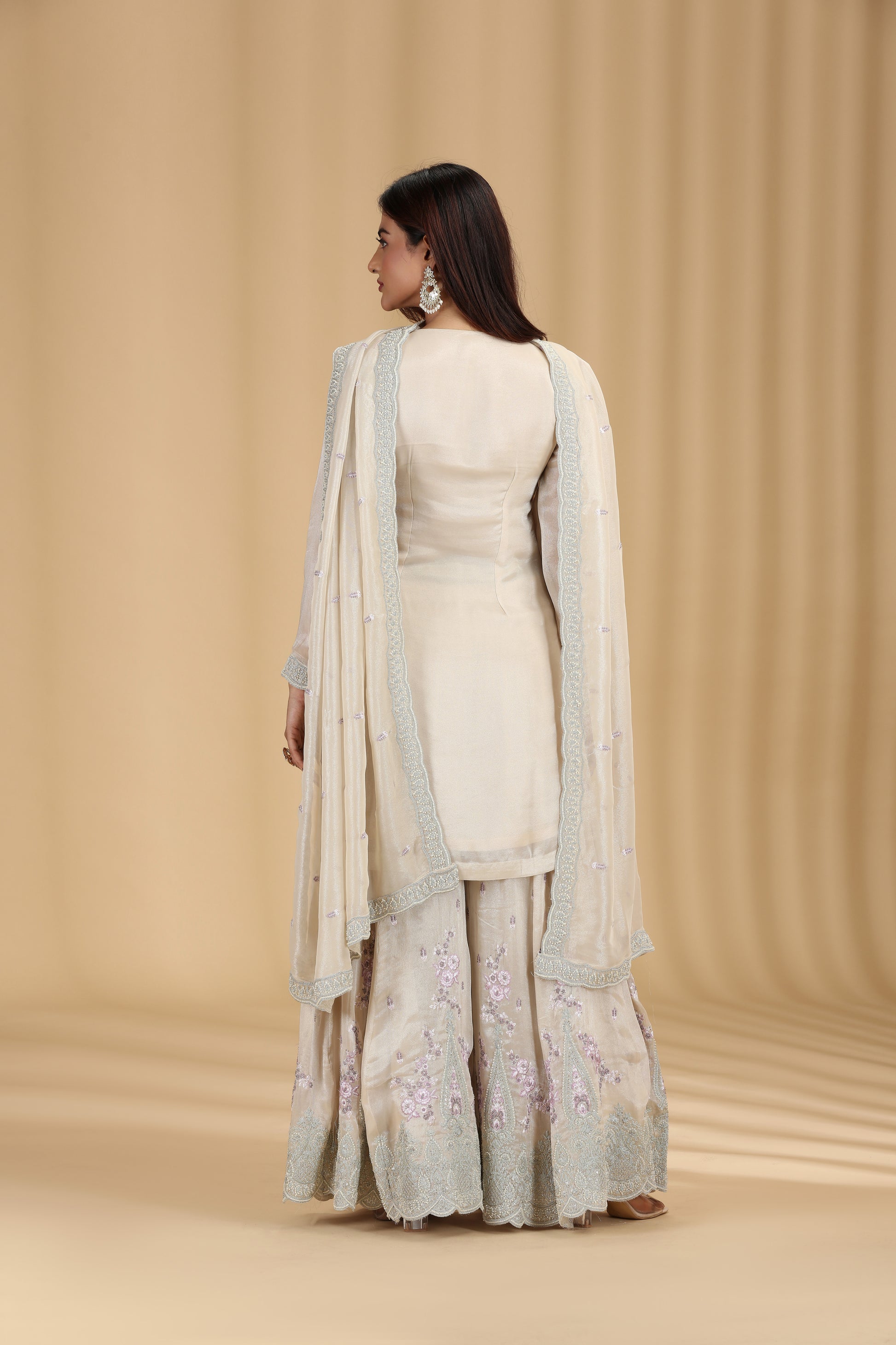 Woman wearing a wedding ready beige tissue salwar suit with resham and sequins work