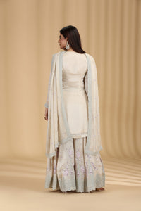 Woman wearing a wedding ready beige tissue salwar suit with resham and sequins work