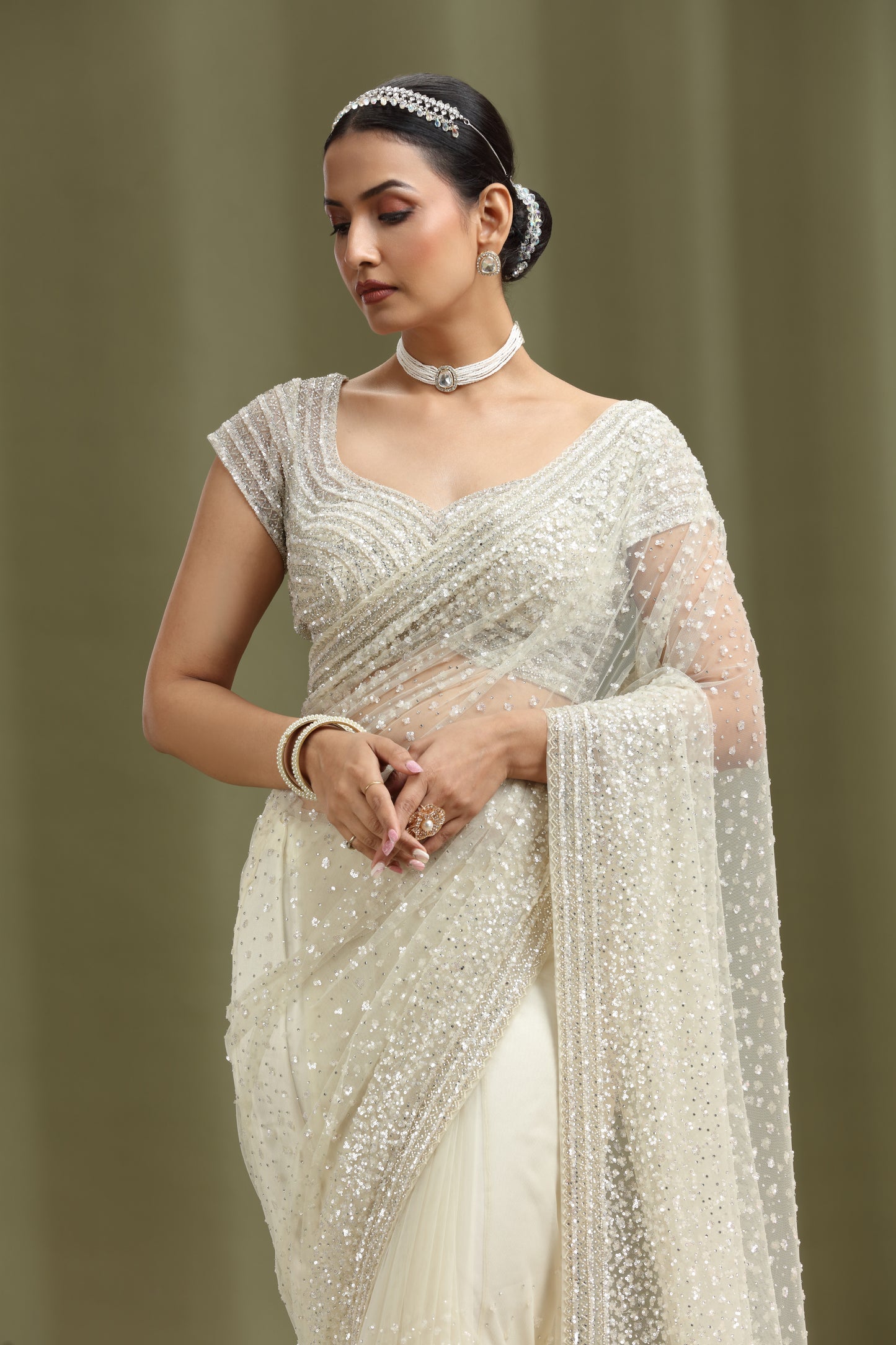 Woman wearing a ivory net white saree with a plain background