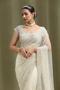 Woman wearing a ivory net white saree with a plain background