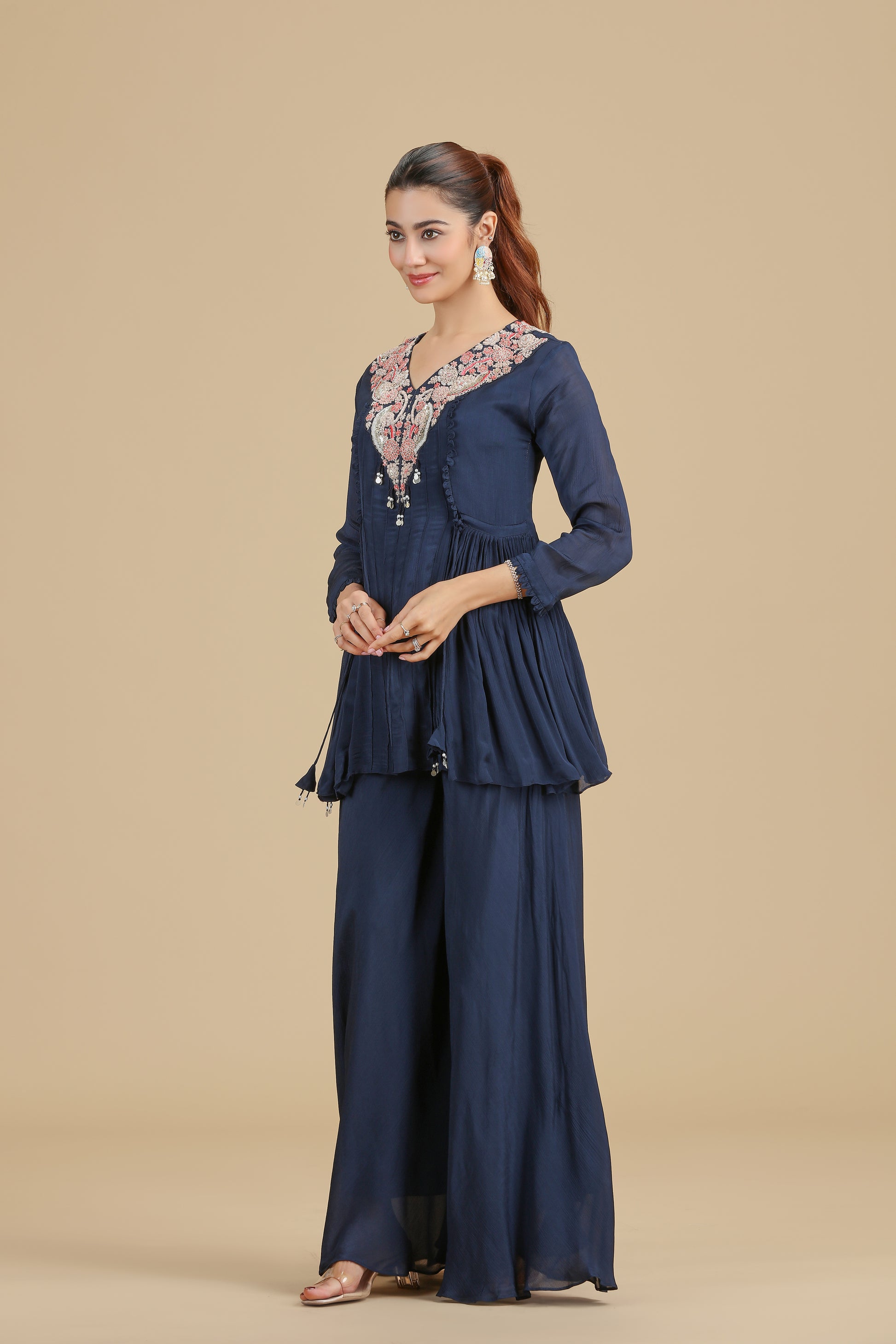 Woman wearing a navyblue chinnon kurta set with floral details on a beige background