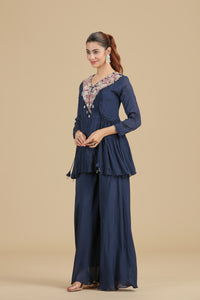 Woman wearing a navyblue chinnon kurta set with floral details on a beige background
