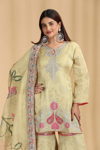 Woman wearing a light green embroidered outfit with a matching dupatta on a beige background