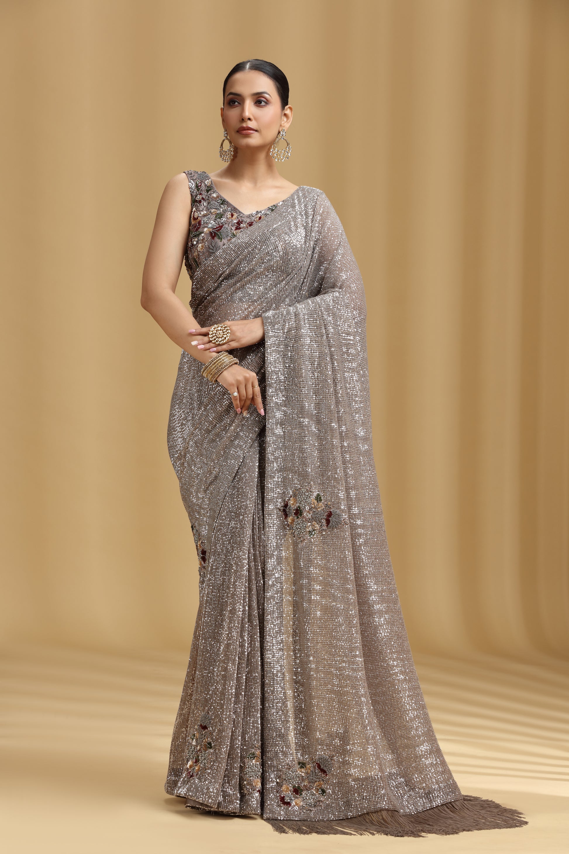 Woman wearing a gray saree with floral patterns on a beige background