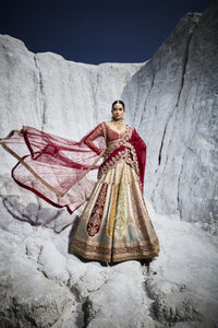 Woman in traditional embroidered lehenga with a red dupatta standing against a snowy mountain backdrop