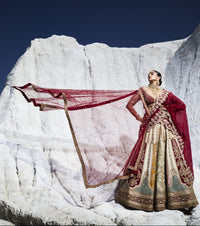 Woman in traditional wedding lehenga with a red dupatta against a snowy mountain backdrop