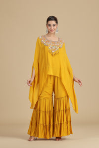 Woman wearing a yellow traditional outfit with floral embroidery on a beige background