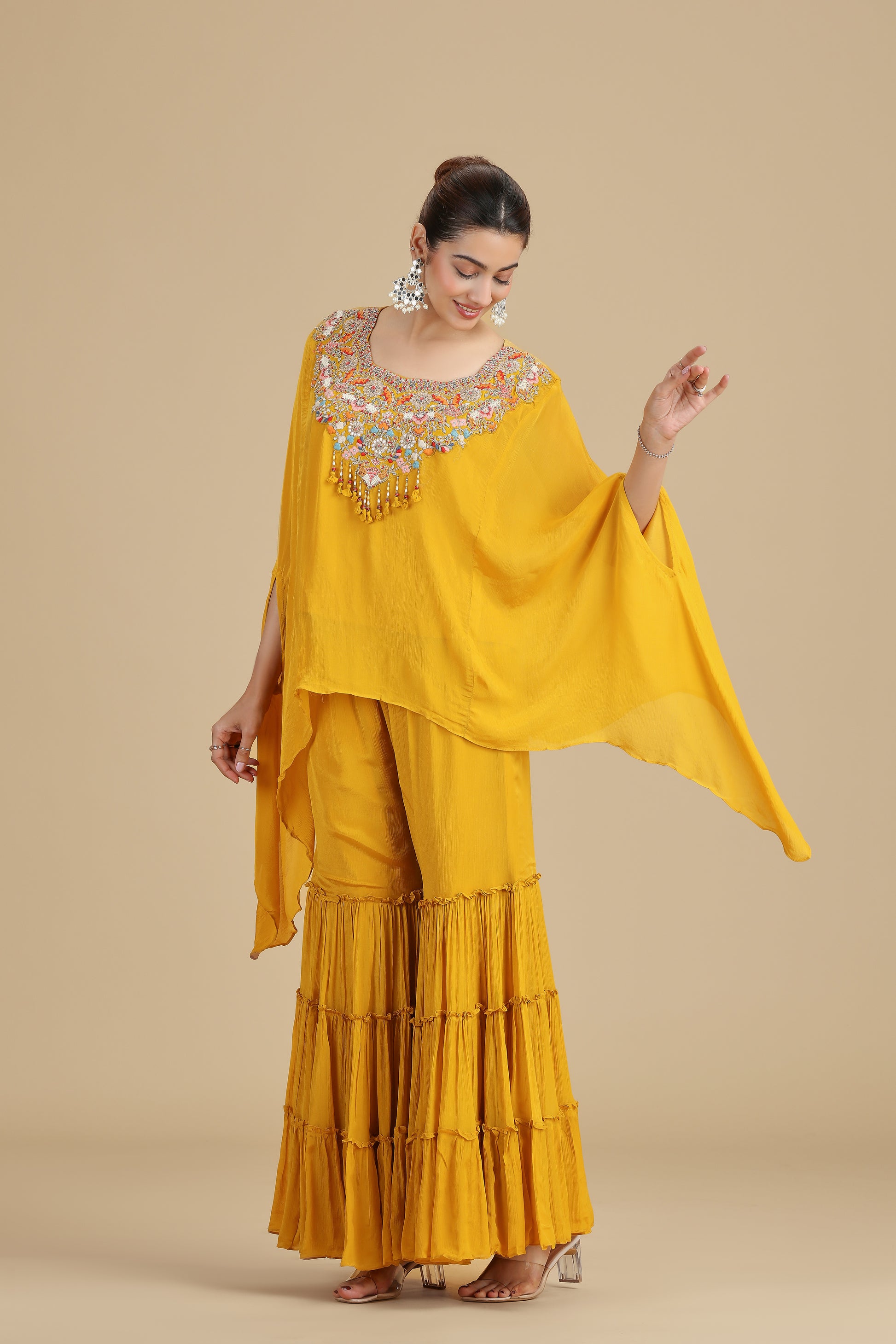 Woman wearing a yellow traditional outfit with an embroidered top on a beige background