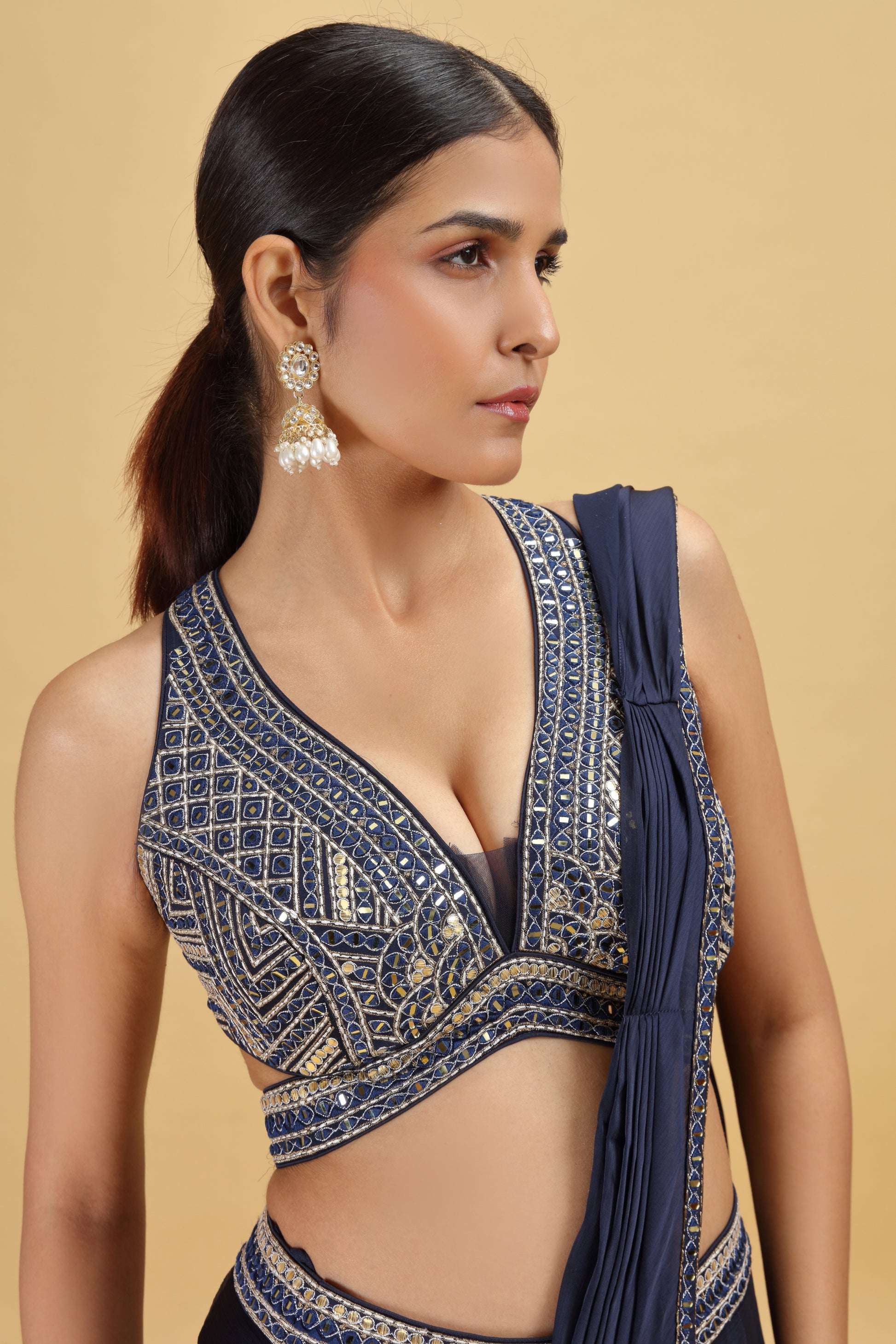 Woman wearing a blue embroidered blouse against with abla and mirror work