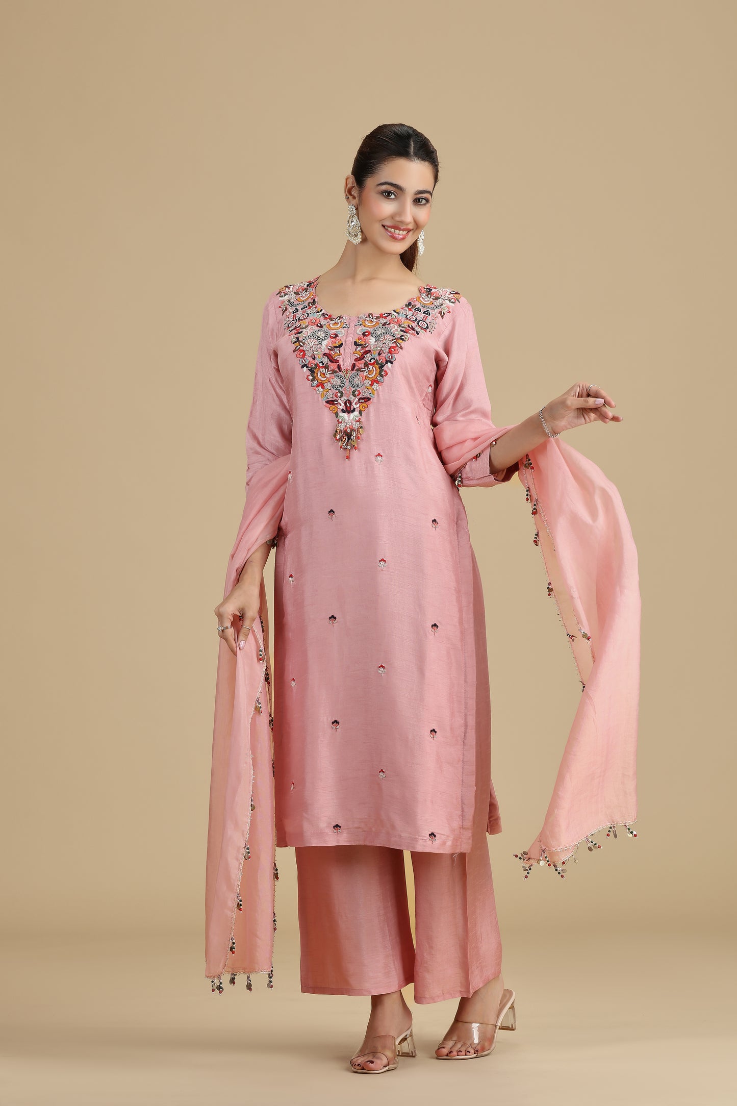 Woman wearing a raw peach kurta set with a beige background