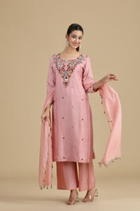 Woman wearing a raw peach kurta set with a beige background