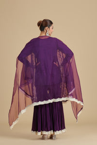Woman wearing a purple traditional kurta set with a sheer dupatta on a beige background