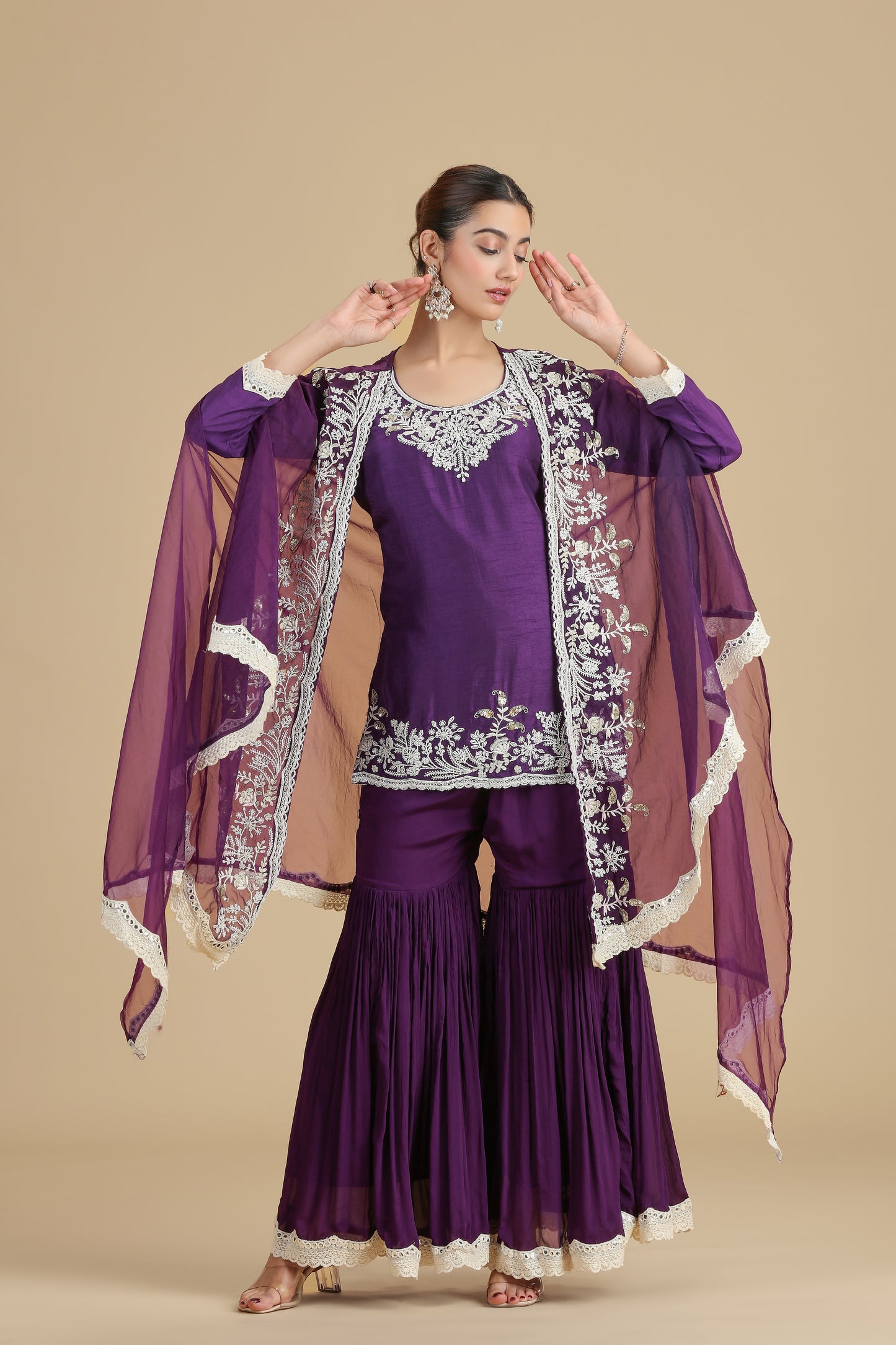 Woman wearing a purple kurta set with white embroidery on a beige background